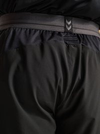 Gros plan sur un short de sport noir avec une taille élastique grise comportant deux flèches en chevrons pointant vers le bas.