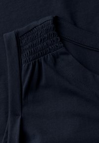 Fondo in felpa blu navy con dettagli in elastico arricciato sul collo, texture liscia e design a scollo a V. Le cuciture delle giunzioni sono visibili.