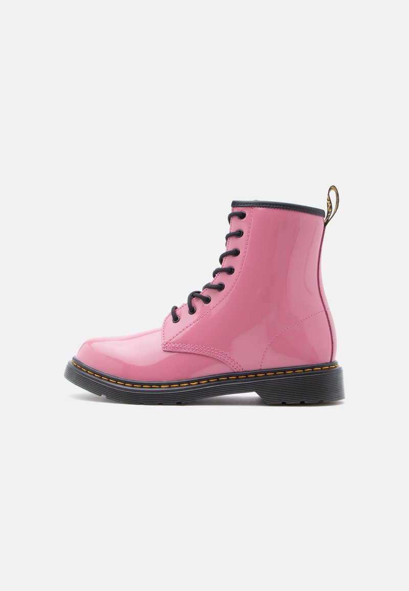 Bottines en cuir verni rose avec lacets noirs, bout rond, surpiqûres jaunes contrastantes et semelle en caoutchouc noire. Dotées d'une languette de tirage.