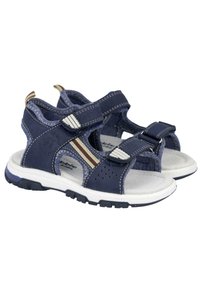 Sandalias azul marino con parte superior sintética, correas ajustables, diseño perforado, plantilla acolchada y suelas de goma blanca. Presenta detalles en marrón.
