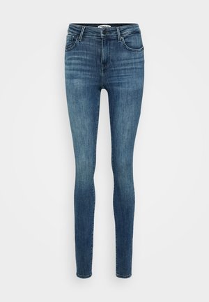 Úzké modré džíny z denimu s bledým ombré, poutky na opasek, předními kapsami a zipem. Materiál má hladkou texturu a mírnou elasticitu.