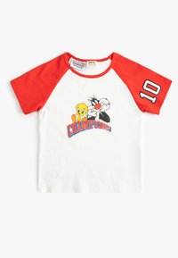 Camiseta de manga corta roja con cuerpo blanco, que presenta a los personajes de dibujos animados Tweety y Sylvester, y la palabra "CAMPEONES" en texto azul.