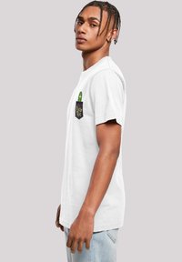 Hvit bomull t-skjorte med korte ermer, med en lomme-design. Lommen viser en grønn tegneserie-agurk med øyne og teksten "Pickle Rick."