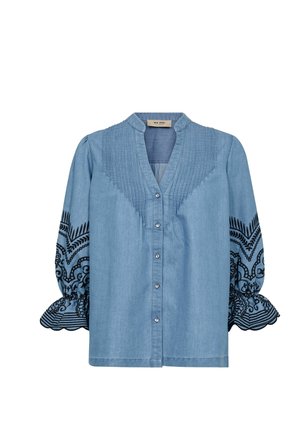 Blouse en denim bleu clair avec des détails de plis sur le yoke, motifs floraux noirs brodés sur les manches trois-quarts bouffantes avec des poignets volantés.