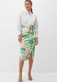 Bloemrijke kokerrok met groene, roze en rode bladeren, met een hoge split. Gepaarde met een witte blouse met knopen. Glad stoffen textuur.