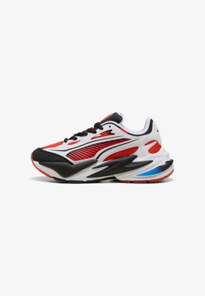 Zapatilla deportiva de corte bajo en rojo, blanco, negro y azul con paneles de malla, parte frontal con cordones y suela acolchada, vista lateral.