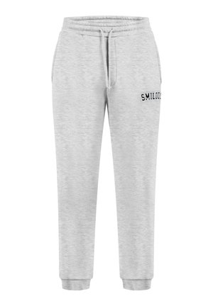 Pantaloni da tuta grigi in cotone con vita elasticizzata, cordino e caviglie elastiche. Presentano la scritta nera "SMILOOD" di lato.