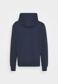 Marinblå huvtröja med långa ärmar, ribbade muddar och nederkant, visad bakifrån mot en enfärgad bakgrund.