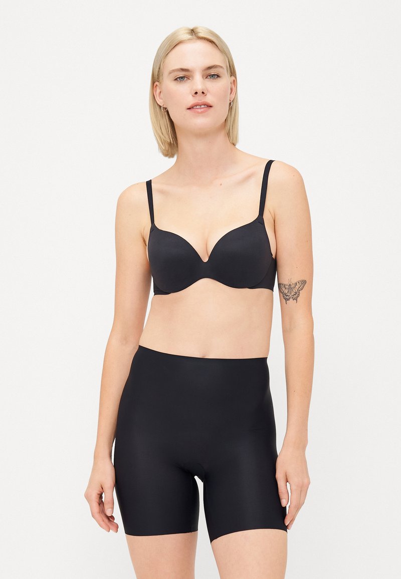 Set di lingerie nera composto da un reggiseno imbottito e liscio con spalline regolabili e pantaloni corti a vita alta in tessuto liscio. Entrambi gli articoli sono senza cuciture.