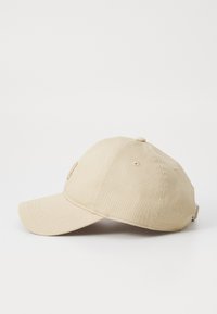 Cappello da baseball in cotone beige con visiera curva, strap regolabile e un piccolo logo ricamato sul davanti. Texture liscia, design classico.
