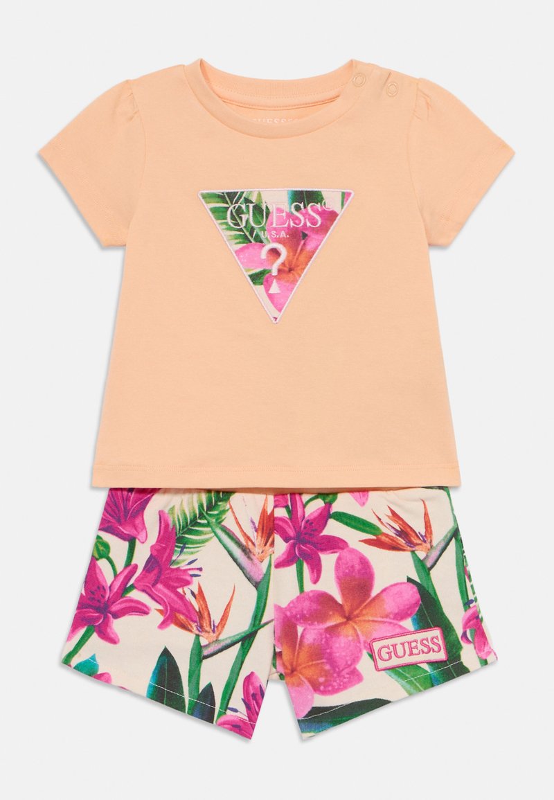 Tricou din bumbac portocaliu cu un logo triunghiular imprimat floral. Asortat cu șorturi cu un tipar floral vibrant în roz și verde, care includ o etichetă cu logo.