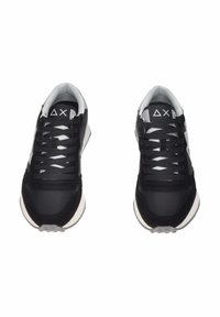 Scarpe sportive nere con tomaia in tessuto a rete e scamosciato, lacci bianchi e una suola intermedia bianca a contrasto. Dettaglio del logo ben visibile sulla linguetta.