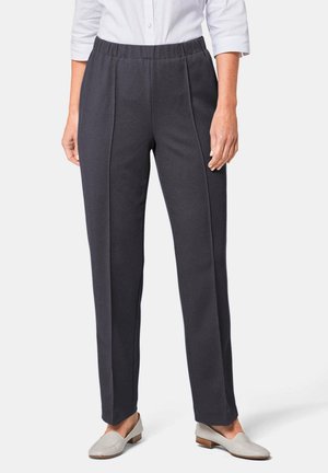 Pantaloni a coste grigi scuri con elastico in vita, presentano due cuciture frontali e gambe a taglio dritto. Indossati con scarpe slip-on grigie chiare.