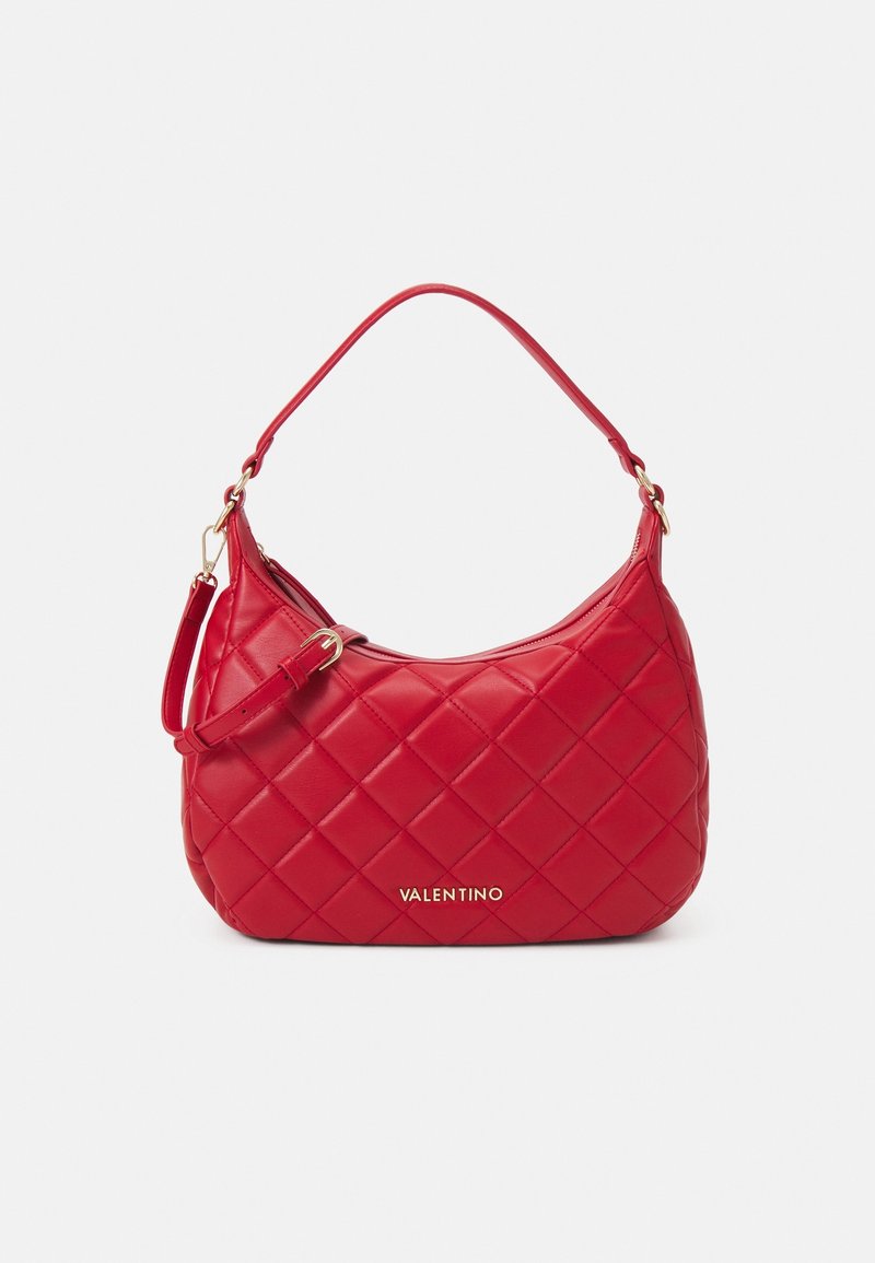 Sac à main en cuir rouge matelassé avec une forme incurvée, doté d'une courte bandoulière et de ferrures dorées. Logo affiché à l'avant.