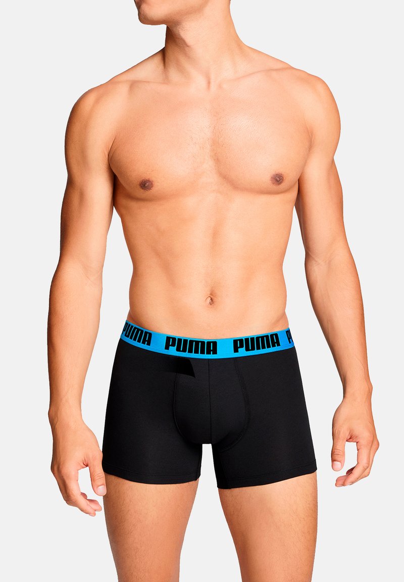 Schwarze Boxer-Slips mit einem blauen elastischen Bund, auf dem "PUMA" in Schwarz gedruckt ist. Glatter Stoff, tailliertes Design und eine vordere Öffnung.