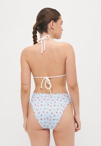 Bikini z modrim karirnim vzorcem, ki vsebuje majhne rdeče češnje, z visokim pasom, vrvico za zavezovanje okoli vratu in gladko teksturo tkanine.