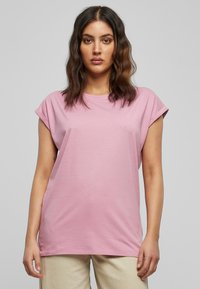 Light pink cotton t-shirt with rolled short sleeves, round neckline, and a relaxed fit. Simple, smooth texture without patterns or accents.