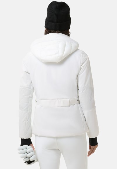 Biała puchowa kurtka z kapturem, z paskiem w talii i pikowanym wzorem. Posiada czarne akcenty na mankietach oraz dzianą czarną czapkę.