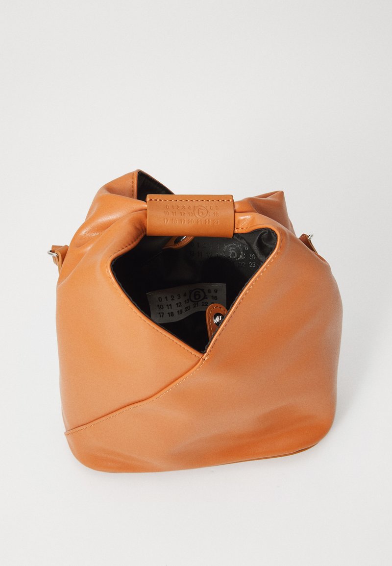 Borsa a tracolla in morbido cuoio beige con apertura superiore che rivela un interno nero e un'etichetta bianca con numeri all'interno, posta su uno sfondo bianco.