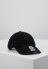 Gorra de béisbol negra hecha de algodón, con un logo bordado, visera curva y correa ajustable. Etiqueta visible en la parte delantera.