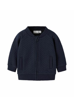 Marineblaues Zip-Jackett mit Fischgrätmuster, gerippten Bündchen und Saum, zwei Fronttaschen, rundem Halsauschnitt und Etikett auf der Innenseite.