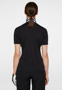 Sort kortærmet polo-shirt med høj krave, der har en zebra-mønstrede bånd. Skjorten har en tætsiddende design og kontrasterende sidepaneler.