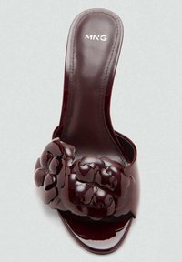 Sandale à glissière en vernis bordeaux avec une finition brillante, de grandes accents floraux et une semelle contournée. Logo de la marque visible sur la semelle intérieure.