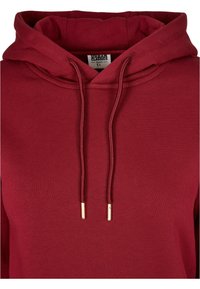 Sudadera burdeos con capucha ajustable. Fabricada en tejido de canalé, presenta extremos de cordón con acentos dorados y un diseño de corte holgado.