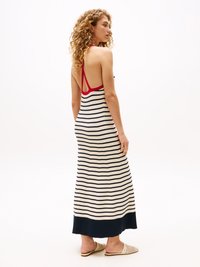 Abito maxi a righe con colori navy e crema, design senza schienale e un accento rosso sul colletto. Tessuto a coste e silhouette fluida.