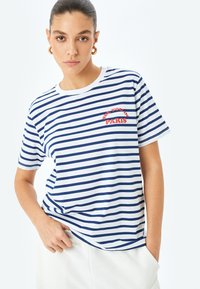 Gestreept katoenen T-shirt in wit en marineblauw, met korte mouwen en ronde hals. "See You in Paris" is in het rood geborduurd.