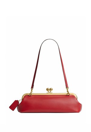 Sac à main en cuir rouge avec une longue bandoulière, une fermeture par boucle dorée et une petite étiquette assortie attachée sur le côté.