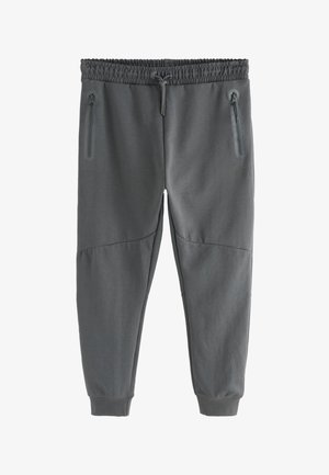 Grå joggingbukser med elastisk taljebånd, snor og to sidelommer med lynlås. Fremstillet af blødt stof med en glat tekstur.