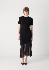 Abito nero con un top a maniche corte in tessuto uniforme e un orlo trasparente a lunghezza ginocchio. Design semplice ed elegante con una silhouette aderente e cuciture nascoste.