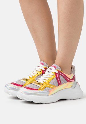 Färgglada sneakers med ett överstycke i nätmaterial, med rosa, gula och silverfärgade detaljer. Tjock vit sula och framträdande snörningssystem. Reflekterande detaljer.