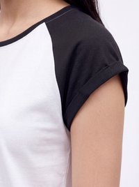 Záber osoby v čierno-bielom raglán tričku s krátkym rukávom a zrolovaným lemom na rukáve.
