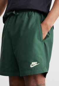 Nike Sportswear FLOW - Pantaloni sportivi - fir