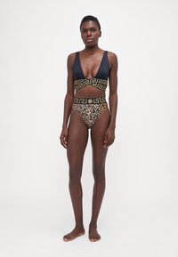 Svart og gull todelt badedrakt med dyp v-hals topp og høy midje bunn med leopardmønster og dekorative belte-detaljer.