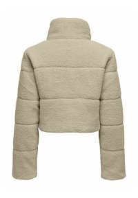 Giacca in pile beige tagliata, con un colletto alto, caratterizzata da una superficie texturizzata e sezioni imbottite, che enfatizzano calore e morbidezza.