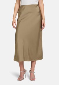 Satin-Midi-Rock in einem sanften Braunton, mit glatter Textur und gerader Silhouette, kombiniert mit silbernen Riemchen-Heels.