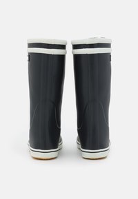 Mustat kumisaappaat, joissa on valkoiset raidat ylhäällä, ja joissa on teksturoitu takaosa ja tasapohja. Sileä materiaali, jolla on hieman kaareva muoto.