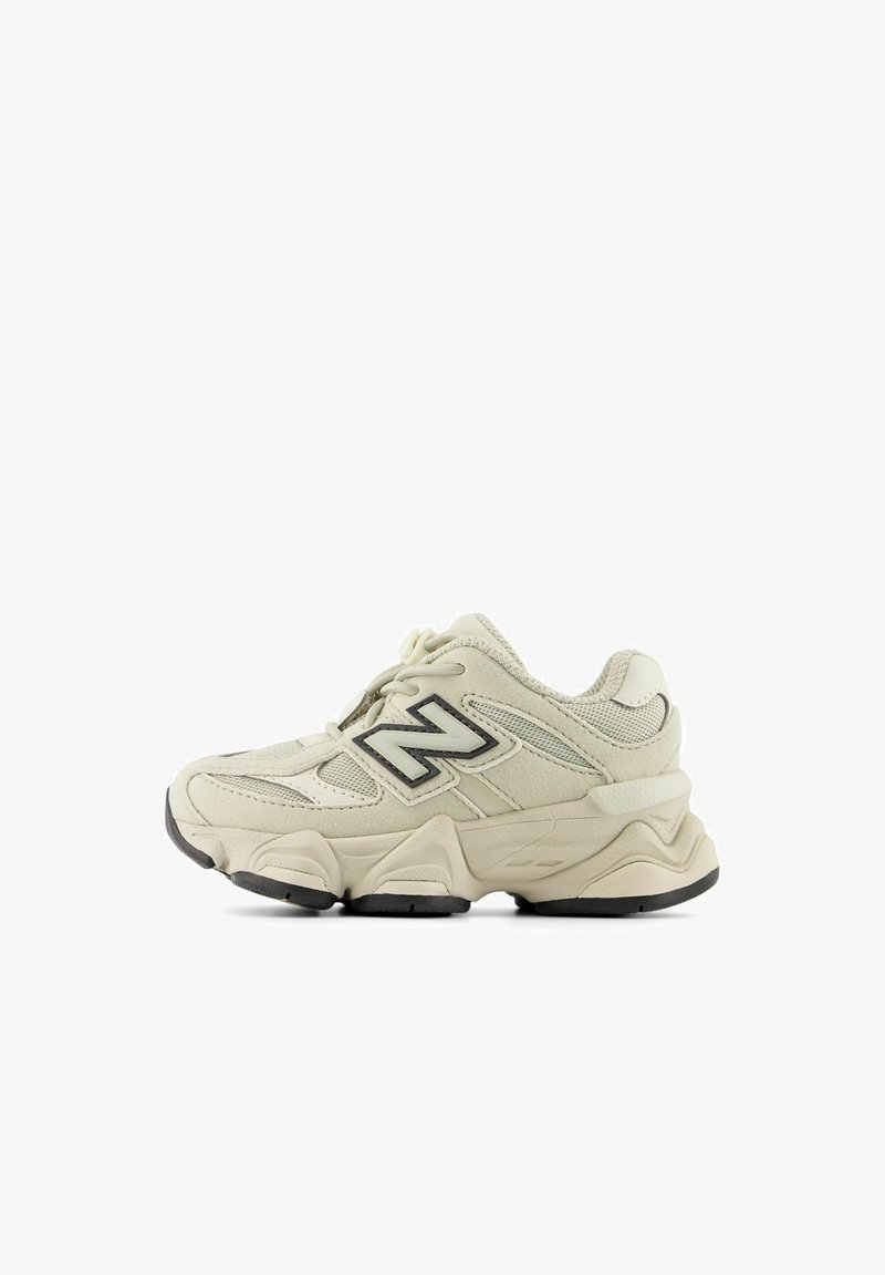 Beige-weißer Sneaker mit Mesh- und Wildlederpaneelen, schwarzem "N"-Logo, gepolsterter Sohle und schwarzer Gummilaufsohle, Seitenansicht.
