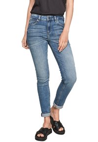 Úzké džíny v světlém modrém denim, s polovičním pasem a designem s pěti kapsami, s jemným vyšisováním a ohrnutými nohavicemi, doplněné černými sandály.