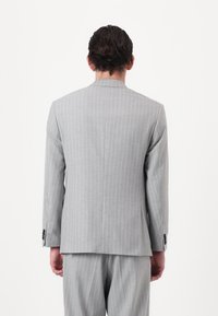 Gray pinstripe suit jacket with a tailored fit, single back vent, and two-button closure. Smooth texture and structured silhouette.