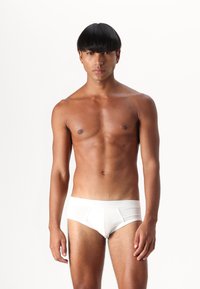 Vita, åtsittande kalsonger gjorda av mjukt och sträckbart tyg. Har en sömlös design med en bekväm midjeresår och minimal täckning.