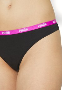 Crni pamučni tangice s širokim ružičastim pojasom na kojem se nalazi "PUMA" logo u bijeloj boji. Dizajn je jednostavan, s glatkim šavovima za udobnost.