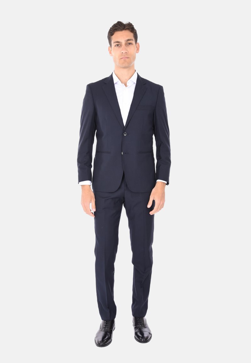 Complete blu navy con giacca a due bottoni, camicia bianca e scarpe eleganti nere. Presenta un design slim fit e rever a l'inglese.