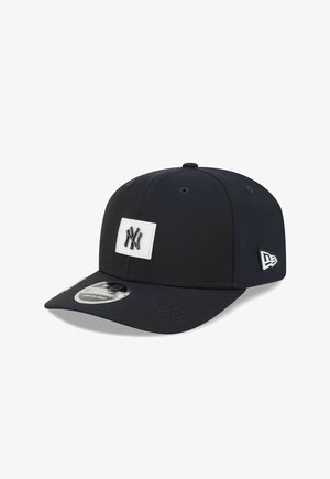 Black baseball cap with New York Yankees logo on front and New Era logo on side, featuring a curved brim and adjustable strap.
