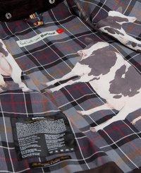 Podszewka kurtki Barbour z dużymi ilustracjami krów na szarym wzorze w kratę, z czarną etykietą pielęgnacyjną na dole.