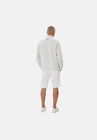 Lichtgrijze sweatshirt met een hoge kraag, gecombineerd met witte shorts en bijpassende schoenen. Eenvoudig, schoon ontwerp zonder zichtbare patronen.