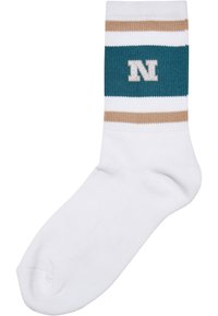 Vit strumpa med en teal-färgad rand som har beige ränder och en vit bokstav "N" i mitten. Materialet ser mjukt och stretchy ut.